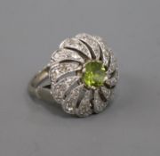 A modern white metal, peridot and diamond pierced circular whorl design dress ring, size K/L.