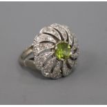 A modern white metal, peridot and diamond pierced circular whorl design dress ring, size K/L.