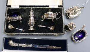 Two silver condiment sets, one cased and a cased paperknife.