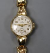 A lady's 9ct gold Tudor manual wind wrist watch, on a 9ct gold bracelet.