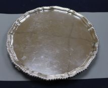 A silver salver with shaped gadrooned rim on three reeded scrolled feet, Birmingham 1937, makers