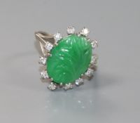 An 18ct white gold, carved oval cabochon jadeite and diamond set ring, size M.