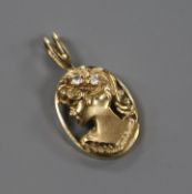 A modern yellow metal and gem set pierced oval pendant, modelled as the bust of a lady to dexter,