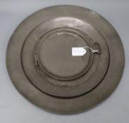 An 18th century pewter charger, two plates and a warming dish Largest 42cm diameter