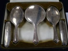 A cased George V silver five piece mirror and brush dressing set, Walker & Hall, Sheffield, 1918, in