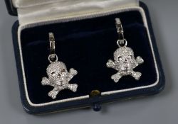 A modern pair of 18ct white gold and diamond encrusted 'skull and crossbones' earrings, in Theo