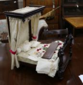 A late Victorian dolls half tester bed with 18th century silk curtains, point de gaze pillows and