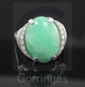 A platinum, cabochon jade and diamond set oval dress ring, the central stone bordered with graduated