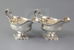 A pair of George III silver pedestal sauceboats by William Skeen, with engraved crest, ornate scroll