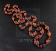 A Chinese amber necklace with forty five graduated oval beads fluted and with prunts at both ends,