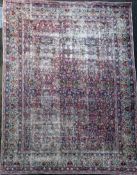 A Kirman ivory ground carpet, with polychrome field of scrolling foliage and five row foliate