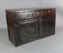 An early 18th century oak dresser base, fitted three long drawers over panelled cupboard doors, on