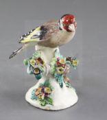 A Derby model of a goldfinch, c.1760-5, perched on a floral encrusted tree branch, patch marks, h.