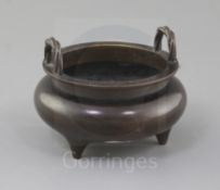 A Chinese bronze tripod censer, with a pair of high looped ropetwist handles, on three tapering