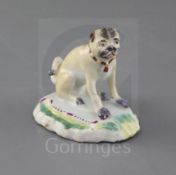A Derby figure of a seated pug, c.1758-60, on a rococo scrollwork base with puce, pale green and