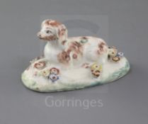 A rare Derby figure of a recumbent spaniel, c.1758-60, on a turquoise fringed oval pad base,