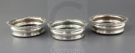 A pair of George III Irish silver mounted wine coasters and one other similar coaster, with shell