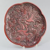 A Chinese red lacquer pentafoil shaped dish, relief decorated with two egrets amid peonies, width