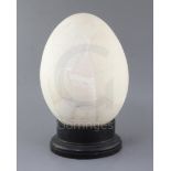 A reconstructed Elephant Bird egg, approximately 31cm, with ebonised wood stand