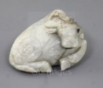 A Chinese pale celadon jade figure of a recumbent buffalo, Ming dynasty, the stone with white
