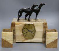 An Art Deco clock set, beige marble with dog surmounts 36cm high, 36cm wide