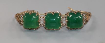 A yellow metal bracelet set with three large faceted green stones.