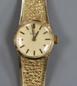 A lady's 9ct gold Omega manual wind wrist watch, on textured 9ct gold Omega bracelet.