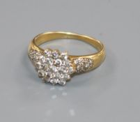 An 18ct gold and diamond cluster ring with diamond set shoulders, size P/Q.