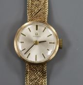 A lady's 9ct gold Tissot manual wind wrist watch on a textured 9ct gold bracelet.