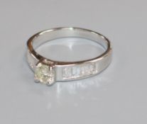 A modern 18ct white gold and single stone diamond ring, with baguette cut diamond set shoulders,
