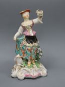 A Derby figure a shepherdess, c.1765-70, standing and holding a garland of flowers, a sheep by her