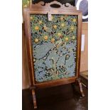 An Edwardian inlaid mahogany firescreen inset woolwork panel in a William Morris-style bird and