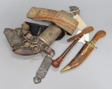 An Omani khanjar in decorative white metal-mounted wooden scabbard on woven belt and two other