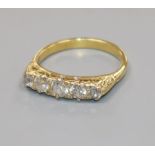 A yellow metal and graduated five stone diamond half hoop ring, size N.