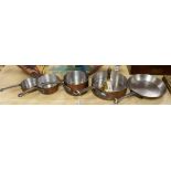 A set of four graduated copper saucepans and a frying pan and a brass bell with turned wood handle