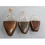 Three 18th century and later leather cased glass flasks, largest 20cm