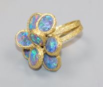 A 1970's? textured 18ct gold and eight stone oval black opal set dress ring, size K/L.