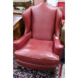 A pair of 1920's burgundy leather wing armchairs, on ball and claw feet