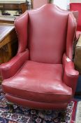 A pair of 1920's burgundy leather wing armchairs, on ball and claw feet