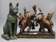 A Thai carved wood group of figures with fighting elephants, a bronzed eagle and a cat