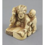 An ivory netsuke of a woman and child, 19th century, kneeling before a large stone, beating cloth,