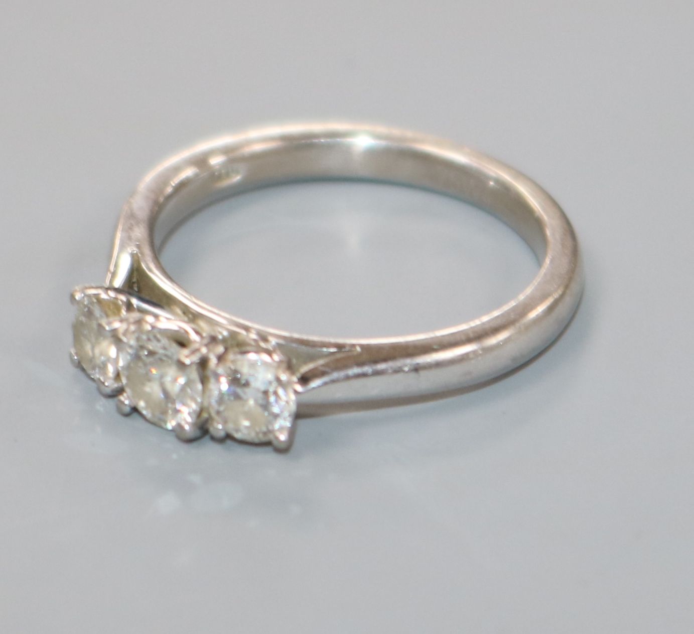 A modern 18ct white gold and three stone diamond ring, size M.