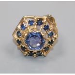 A yellow metal and sapphire set hexagonal openwork cluster ring, size J.