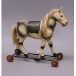 An early 20th century toy horse on wheels height 30cm