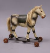 An early 20th century toy horse on wheels height 30cm