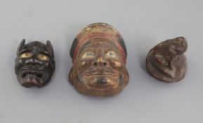 A Japanese bamboo seal in the form of a dog and two wood masks, 19th/20th century, the larger mask