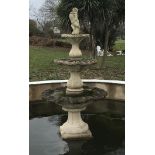 A reconstituted stone three tier garden fountain, surmounted by a putti holding a dolphin This lot