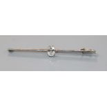 A yellow metal and solitaire oval cut diamond set bar brooch, the stone weighing approximately 0.