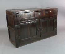 An early 18th century oak dresser base, fitted three long drawers over panelled cupboard doors, on