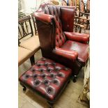 A buttoned red leather wing back armchair and footstool